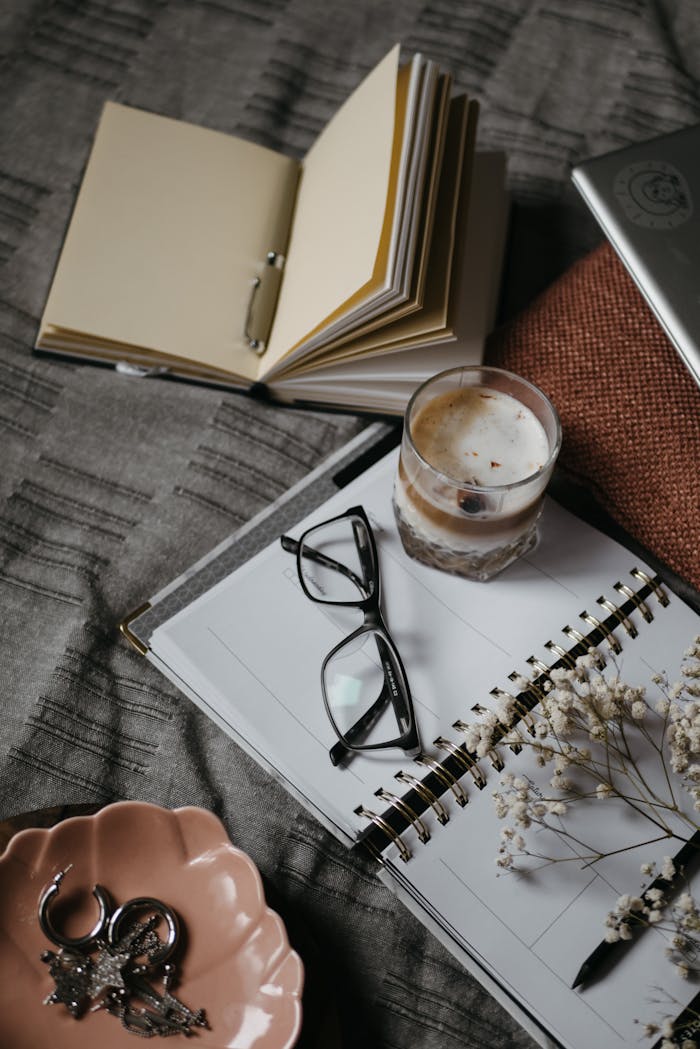 A warm and cozy home workspace featuring a notebook, coffee, and reading glasses.